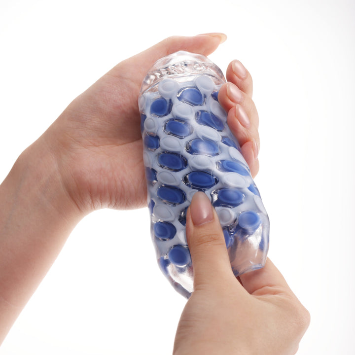 Mains pressant le masturbateur TENGA ARTE Marine Weave pour montrer sa souplesse
