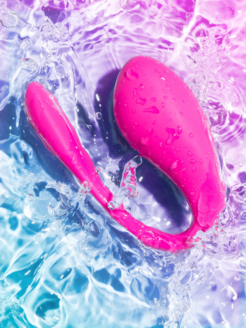 Un gros plan du vibromasseur Jive 2 de couleur rose électrique, submergé dans l'eau, mettant en avant son étanchéité et son design robuste pour une utilisation quotidienne et un nettoyage facile.